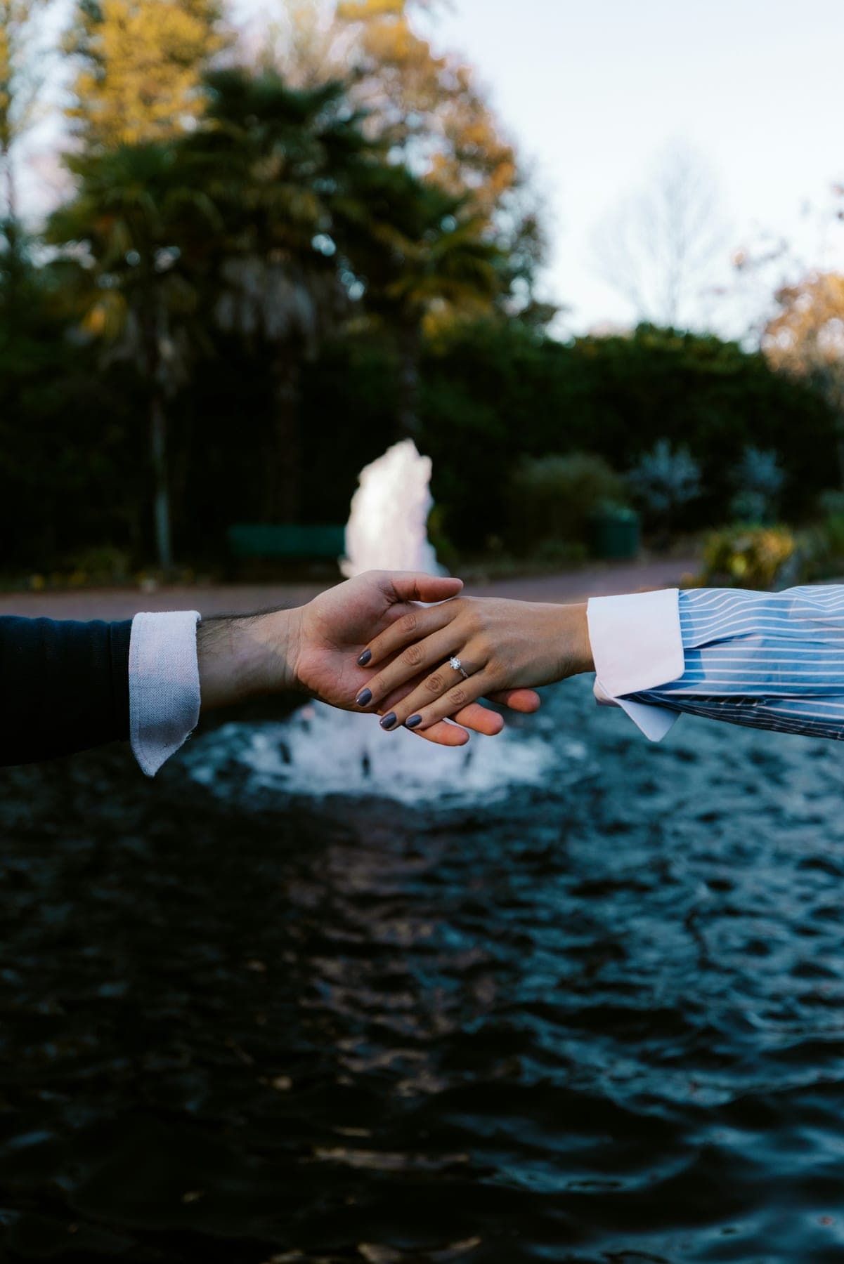 Couple holding hands near a park fountain